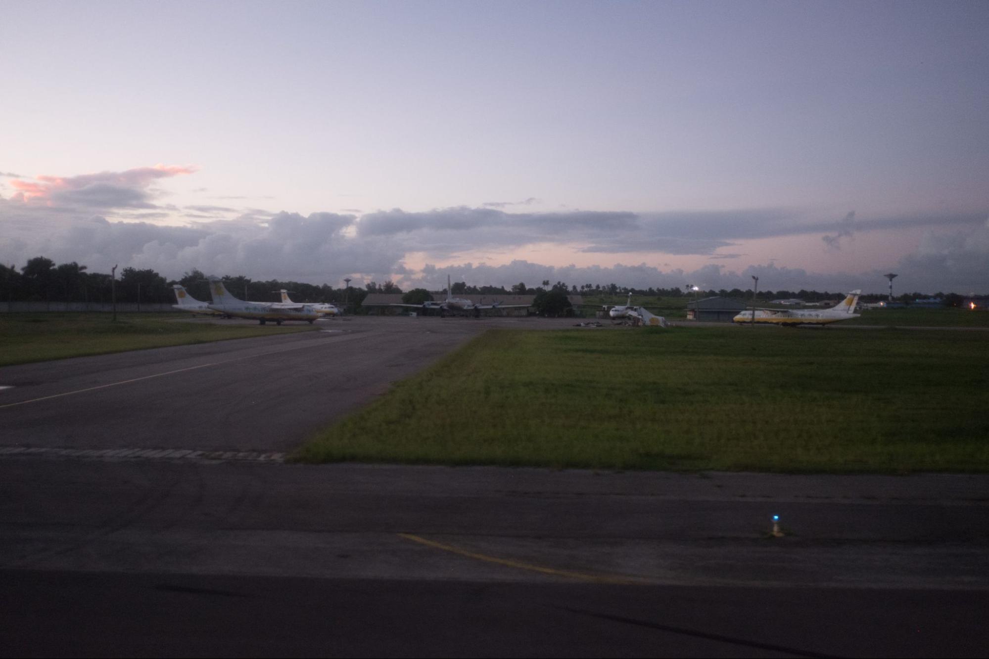 The original challenge photograph: small turboprop aircraft parked on a wet apron at dusk, taken from inside a taxiing aircraft.